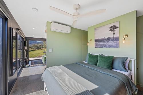 a bedroom with a large bed with green walls at Jinibara Cottage in Conondale