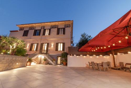 a building with a patio with chairs and a red umbrella at VILLA AGOSTINO LUXURY B&b in Vico Equense