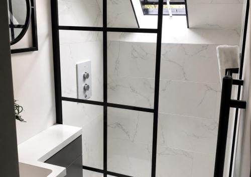 a bathroom with a shower with white marble walls at Plgs and Blankets in Pucklechurch
