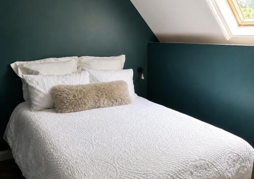 a bedroom with a white bed with a blue wall at Plgs and Blankets in Pucklechurch