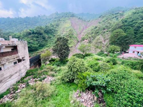 a view of a mountain with houses and trees at Kaushalya River View in Solan