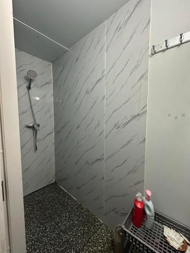 a bathroom with a shower with a gray marble wall at Mays Hostel in Hua Hin