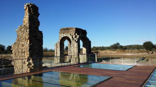 an outdoor deck with an old building and an arch at El Romero in Hervás