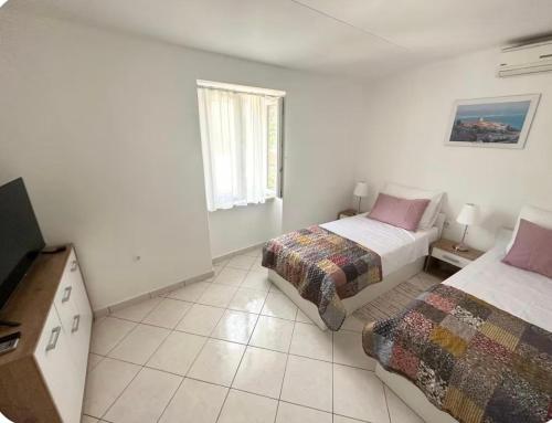 a bedroom with two beds and a tv in it at Apartman Batelan in Brseč