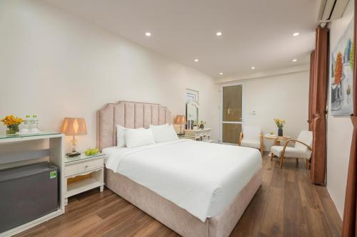 a bedroom with a large white bed and a desk at Hanoi Better Hotel & spa in Hanoi