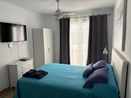 a bedroom with a blue bed and a window at Marina Beach-Apartamentos Tahiche in Costa Teguise