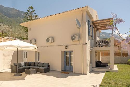 a white house with a couch and an umbrella at Casa di Cona Lourdas in Lourdata
