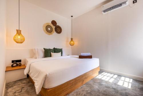 a bedroom with a large white bed and pendant lights at Alcazaba Resort Lombok in Kuta Lombok