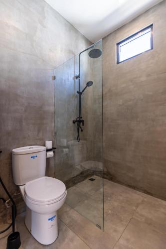 a bathroom with a toilet and a glass shower at Alcazaba Resort Lombok in Kuta Lombok