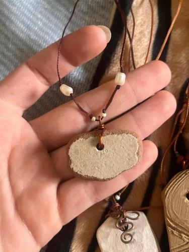 a hand holding a necklace with a stone on it at Clinica apartments in Bologna