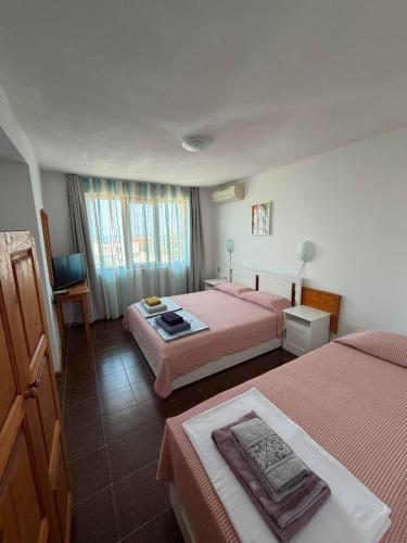 a hotel room with two beds with pink sheets at Guest House Karavida in Sinemorets