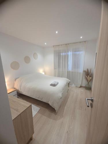 ein Schlafzimmer mit einem weißen Bett und einem Fenster in der Unterkunft Vertu'Ose avec jacuzzi in Morbier