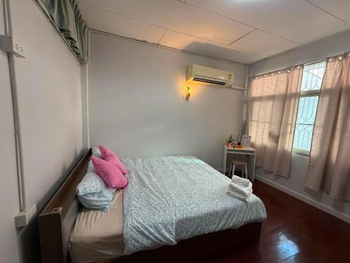 a bedroom with a bed with pink pillows on it at Casa Nicola BKK in Ban Na Song
