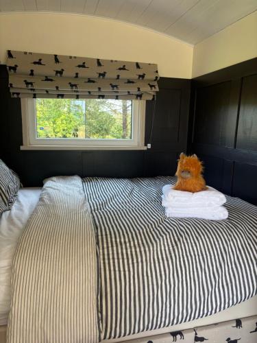 a bed with a stuffed animal sitting on top of it at Blackthorn and Rose Shepherds Huts in Scribbagh