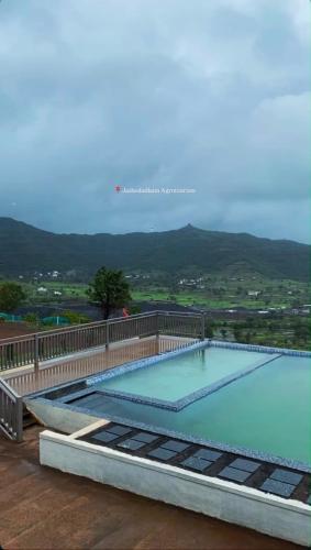 a large swimming pool sitting on top of a house at Jashoda Dham Agro Tourism in Pune