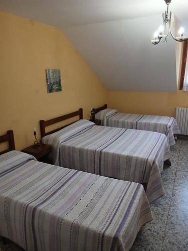 drie bedden in een hotelkamer met gestreepte lakens bij Pinarillos in Sarvisé