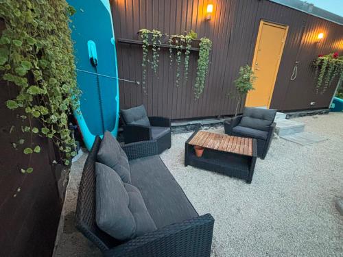a patio with chairs and a table and a surfboard at Namiņš in Ragaciems