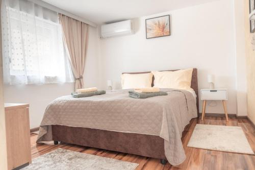 a white bedroom with a large bed and a window at Nora Apartments in Jagodina