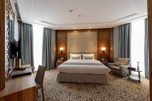 a hotel room with a large bed and a chair at Taj Jeddah in Jeddah