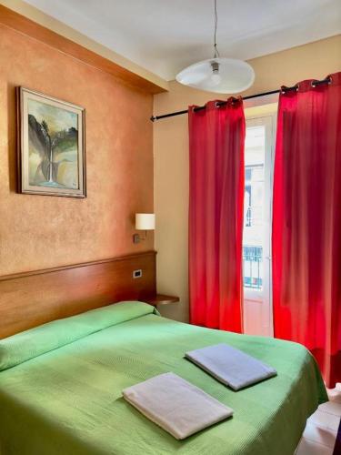 a bedroom with a green bed and red curtains at Innpiero in Taormina