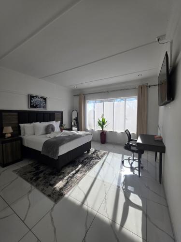 a bedroom with a bed and a desk and a window at Flourish Haven Escape in Germiston