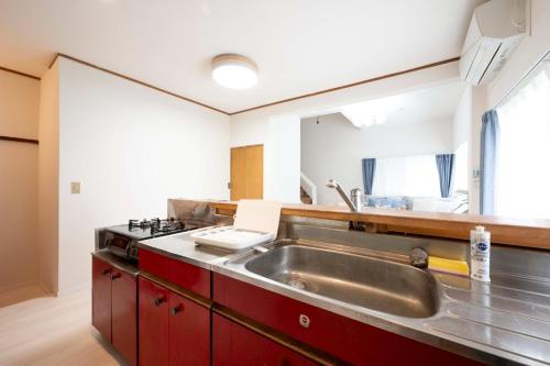 a kitchen with a stainless steel sink and red cabinets at 横須賀-1軒家2棟 in Yokosuka