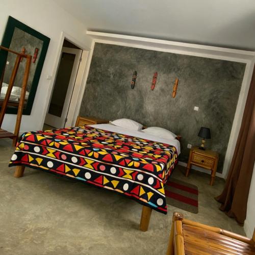 a bedroom with a bed with a colorful blanket at Hotel PZero in São Tomé