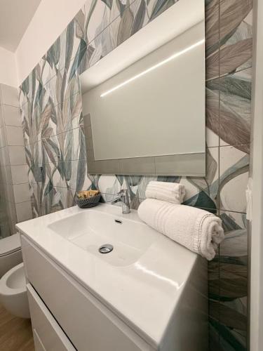 a bathroom with a white sink and a mirror at Orchidea Apartments in Sorso