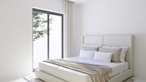 a white bedroom with a large bed with white pillows at Apartment am Moosrain in Eitting