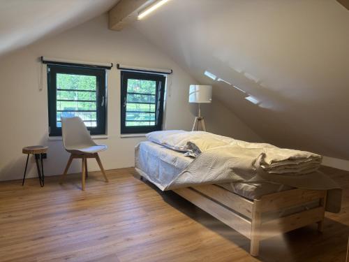 a bedroom with a bed and a chair and windows at Sportchalet Bergkristall regio Nassfeld Presseggersee in Kirchbach
