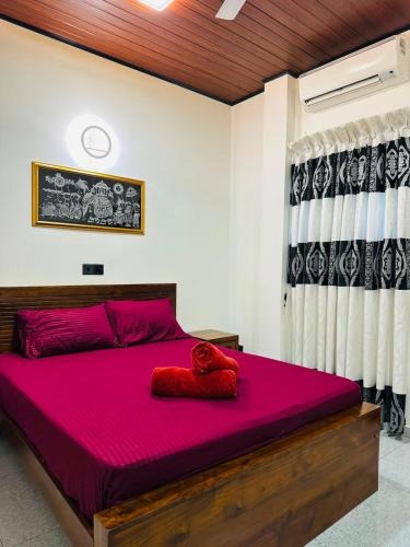 a bedroom with a large bed with red sheets at Feather Villa in Talpe