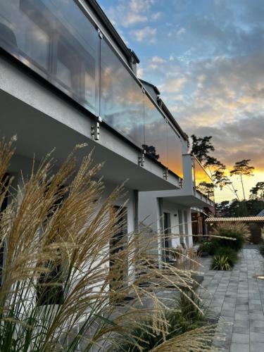 a house with a glass facade with grass at Apartamenty Marco Polo in Dziwnówek