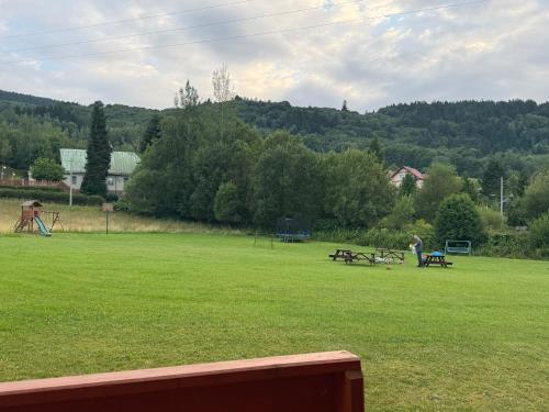 a park with benches and picnic tables in the grass at Domki na Podgórzu in Duszniki Zdrój