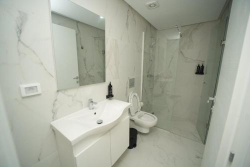 a white bathroom with a sink and a toilet at The Calm Coast Studio in Harqalah