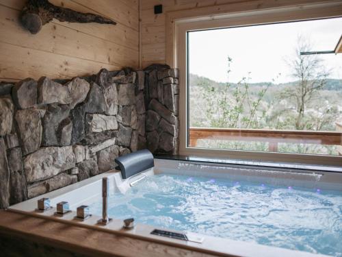 eine große Badewanne in einem Raum mit Fenster in der Unterkunft Romantikchalet Vogelnest mit Whirlpool, Kamin, Balkon & Terrasse in Vorra