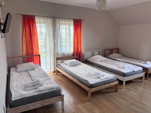 three beds in a room with red curtains at Zajazd Bachus in Czarnocin