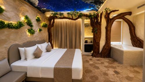 a bedroom with a bed and trees and a bath tub at Dragonfly Hotel - The Art Hotel in Mumbai