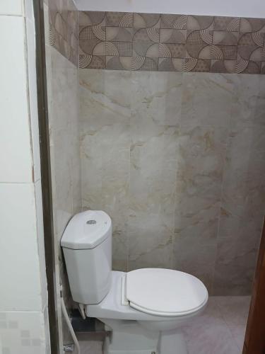 a bathroom with a white toilet and a tiled wall at The Emerald Ceylon - Colombo in Pannipitiya