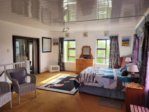 a bedroom with a bed and a chair and windows at Visvanger self catering in Britannia Bay