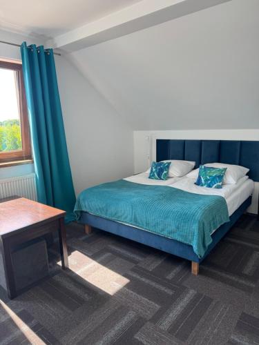 a bedroom with a bed with blue curtains and a table at Hawira in Mielno