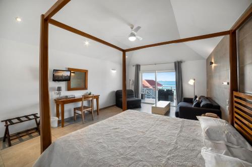 a bedroom with a large bed and a living room at Hôtel Baie des Anges in Gustavia