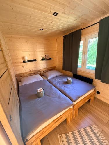 a bed in a wooden cabin with two cups on it at Ubytovanie Lišov 3 - Tiny House in Lišov