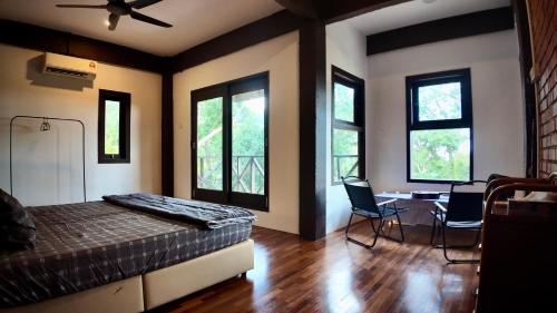 a bedroom with a bed and two chairs and windows at Samwise Escapade Hillside Guesthouse - Master Room in Kampong Perlis