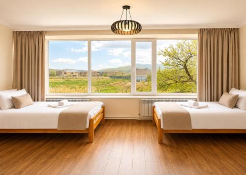 two beds in a room with a large window at Hotel Basen in Sisian