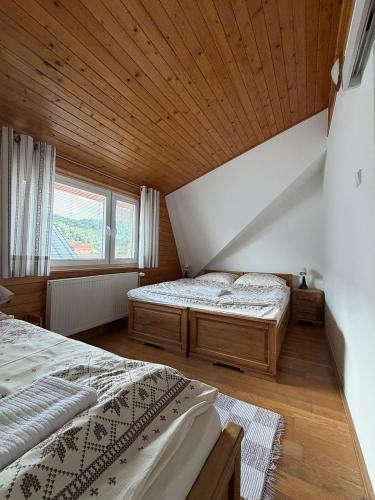 two beds in a bedroom with a wooden ceiling at Apartmány Hrady in Zuberec