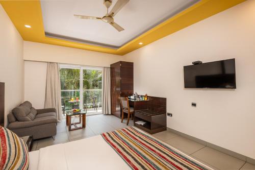 a living room with a couch and a tv on a wall at Regenta Central North Goa, Arpora in Arpora