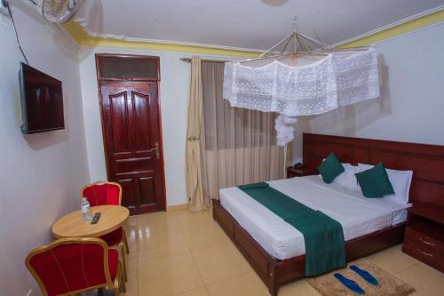 ein Schlafzimmer mit einem Bett, einem Tisch und Stühlen in der Unterkunft FortBreeze Hotel in Fort Portal