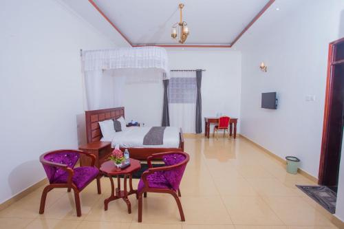 ein Schlafzimmer mit einem Bett, einem Tisch und Stühlen in der Unterkunft FortBreeze Hotel in Fort Portal