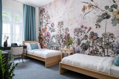 a room with two beds and a floral wallpaper at Hotel Botanica by goodnite cz in Brno