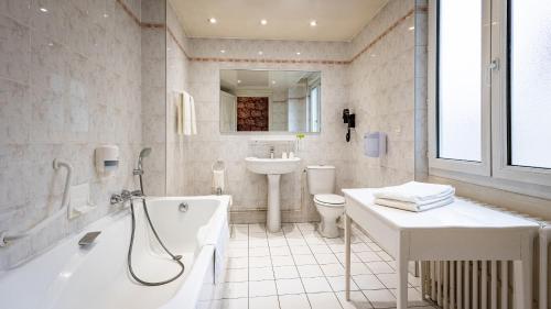 a bathroom with a tub and a sink and a toilet at Hotel Du Nord in Besançon